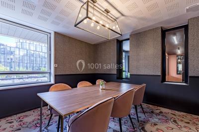 Salle de réunion moderne avec table en verre, chaises violettes, écran mural et fenêtres laissant entrer la lumière…