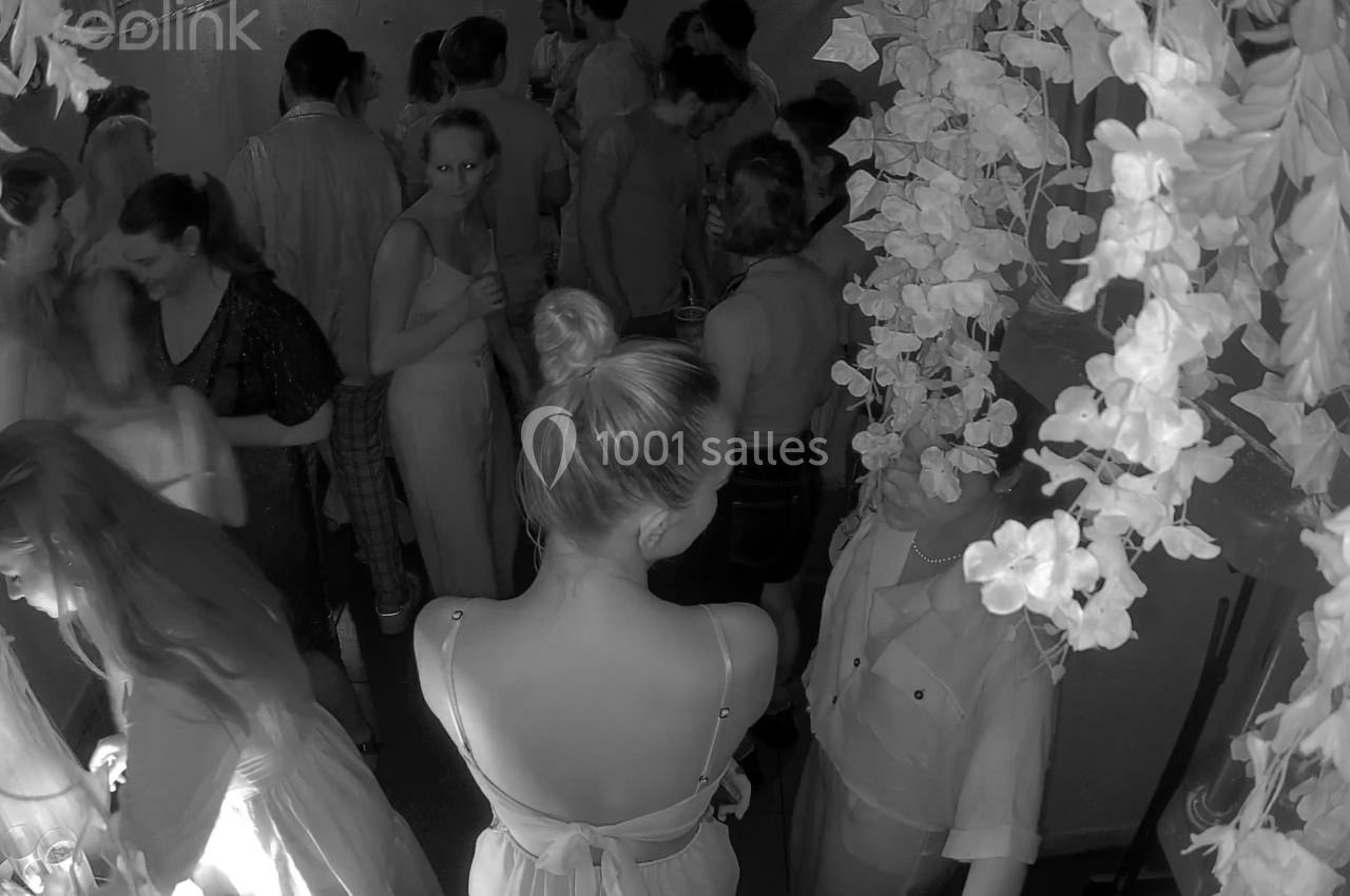 Groupe de personnes dans un espace clos, éclairé faiblement, avec des décorations florales en premier plan.