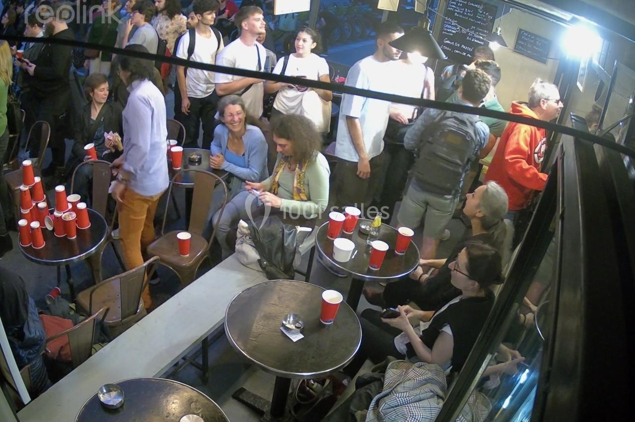 Groupe de personnes discutant et socialisant dans un café animé, avec des gobelets rouges sur les tables.