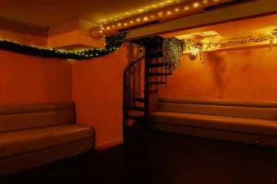 Verres de cocktails variés, dont des shots avec citrons verts et des spritz orange, posés sur des tables en bois.