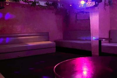 Verres de cocktails variés, dont des shots avec citrons verts et des spritz orange, posés sur des tables en bois.