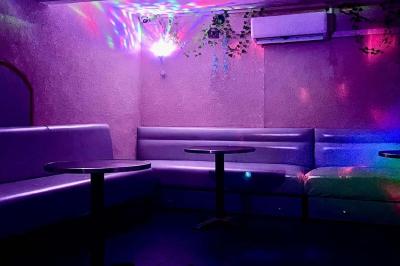 Verres de cocktails variés, dont des shots avec citrons verts et des spritz orange, posés sur des tables en bois.