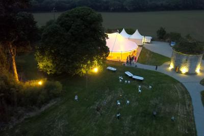 Miniature Location salle Milizac (Finistère) - Domaine de Keranflec'h #24 Structure en bois avec un toit tendu, installée dans un espace extérieur verdoyant et ensoleillé.