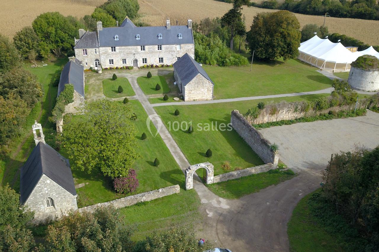 Vue aérienne d'un manoir en pierre entouré de jardins, d'annexes, d'une tente blanche et de champs.