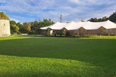 Miniature Location salle Milizac (Finistère) - Domaine de Keranflec'h #45 Structure en bois avec un toit tendu, installée dans un espace extérieur verdoyant et ensoleillé.