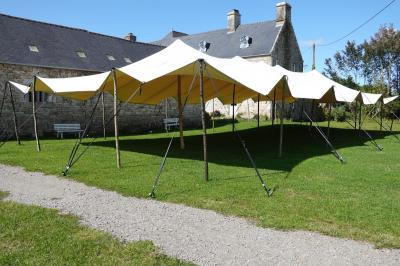Miniature Location salle Milizac (Finistère) - Domaine de Keranflec'h #55 Structure en bois avec un toit tendu, installée dans un espace extérieur verdoyant et ensoleillé.