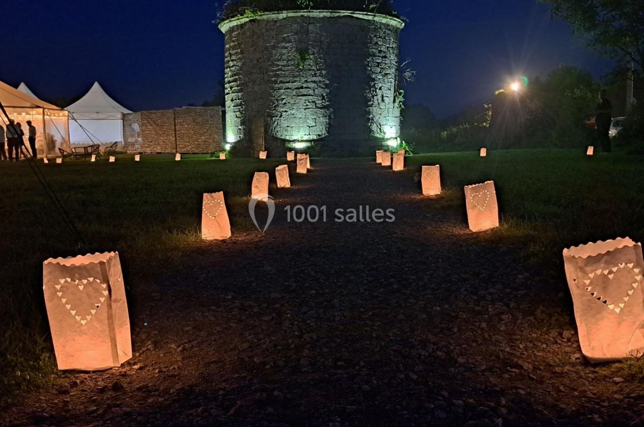 Chemin éclairé par des lanternes en papier décorées de cœurs, menant à une tour illuminée de nuit.