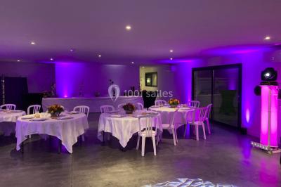 Salle de réception lumineuse avec tables rondes décorées de nappes blanches, fleurs et vaisselle élégante.