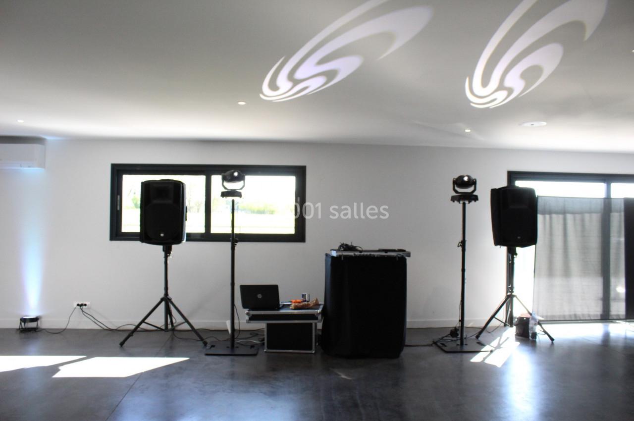 Équipement de sonorisation et éclairage installé dans une salle lumineuse avec fenêtres et sol en béton.