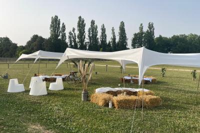 Salle de réception lumineuse avec tables rondes décorées de nappes blanches, fleurs et vaisselle élégante.