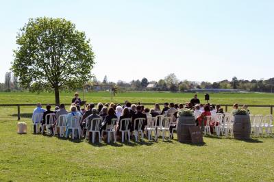 Salle de réception lumineuse avec tables rondes décorées de nappes blanches, fleurs et vaisselle élégante.