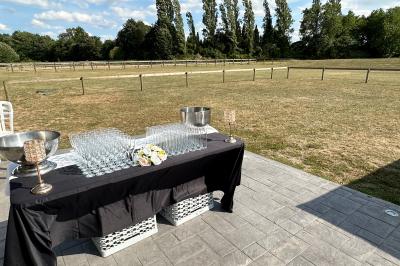 Salle de réception lumineuse avec tables rondes décorées de nappes blanches, fleurs et vaisselle élégante.