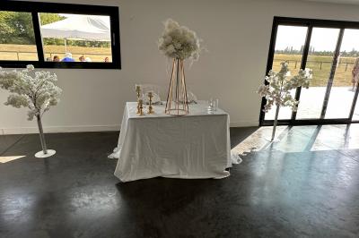 Salle de réception lumineuse avec tables rondes décorées de nappes blanches, fleurs et vaisselle élégante.