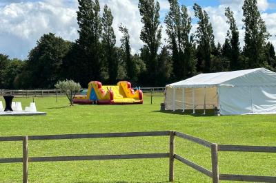 Salle de réception lumineuse avec tables rondes décorées de nappes blanches, fleurs et vaisselle élégante.
