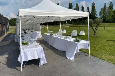 Salle de réception lumineuse avec tables rondes décorées de nappes blanches, fleurs et vaisselle élégante.