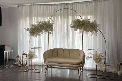 Salle de réception lumineuse avec tables rondes décorées de nappes blanches, fleurs et vaisselle élégante.