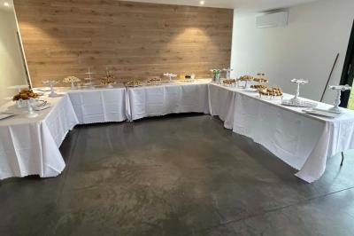 Salle de réception lumineuse avec tables rondes décorées de nappes blanches, fleurs et vaisselle élégante.
