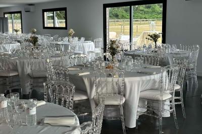Salle de réception lumineuse avec tables rondes décorées de nappes blanches, fleurs et vaisselle élégante.