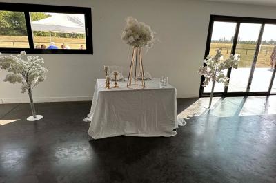 Salle de réception lumineuse avec tables rondes décorées de nappes blanches, fleurs et vaisselle élégante.