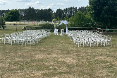 Salle de réception lumineuse avec tables rondes décorées de nappes blanches, fleurs et vaisselle élégante.
