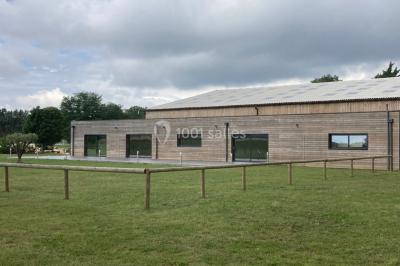 Lit double avec draps gris et oreillers roses, encadré par deux appliques murales sur un mur en bois clair.