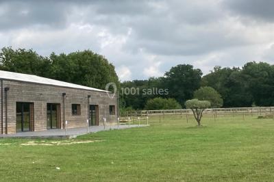 Lit double avec draps gris et oreillers roses, encadré par deux appliques murales sur un mur en bois clair.