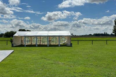 Lit double avec draps gris et oreillers roses, encadré par deux appliques murales sur un mur en bois clair.