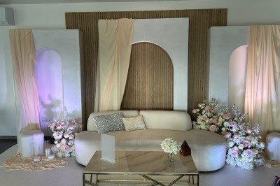 Salle de réception décorée avec des tables alignées, nappes blanches, chaises en bois et centre de table floral.