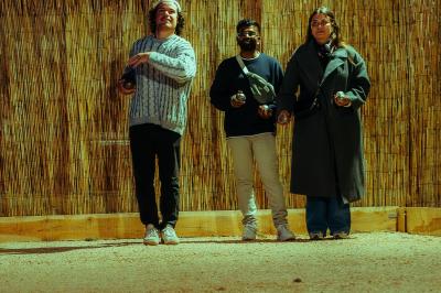 Salle lumineuse avec murs rouges, tables hautes en bois, tabourets métalliques et décorations murales colorées.