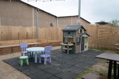 Salle lumineuse avec murs rouges, tables hautes en bois et métal, tabourets, affiches décoratives et luminaires modernes.
