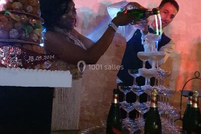 Deux bouteilles de champagne versent simultanément du vin dans une pyramide de coupes en verre.
