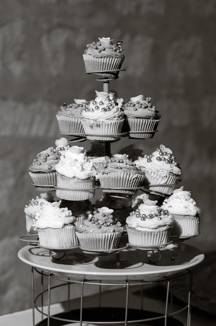 Présentoir à plusieurs étages garni de cupcakes décorés de perles et de fleurs en sucre.