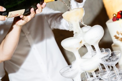 Deux bouteilles de champagne versent simultanément du vin dans une pyramide de coupes en verre.