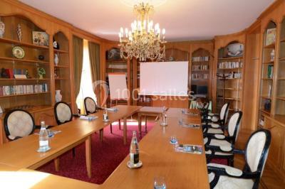 Chambre en bois avec baignoire sur pied, lit double, bureau, fauteuils et grande fenêtre donnant sur l'extérieur.