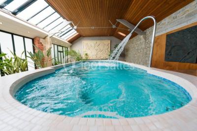 Chambre en bois avec baignoire sur pied, lit double, bureau, fauteuils et grande fenêtre donnant sur l'extérieur.