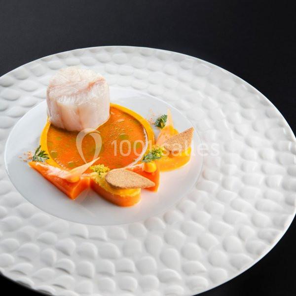 Plat gastronomique avec un médaillon de poisson, purées colorées, sauce orange et garnitures décoratives sur une assiette…