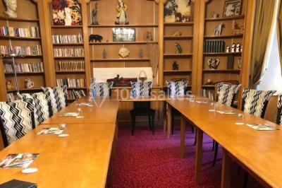 Chambre en bois avec baignoire sur pied, lit double, bureau, fauteuils et grande fenêtre donnant sur l'extérieur.