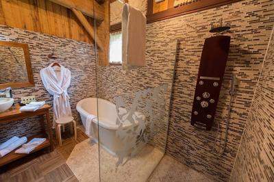 Chambre en bois avec baignoire sur pied, lit double, bureau, fauteuils et grande fenêtre donnant sur l'extérieur.