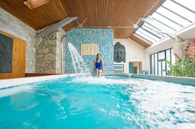 Chambre en bois avec baignoire sur pied, lit double, bureau, fauteuils et grande fenêtre donnant sur l'extérieur.