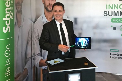 Un homme en costume tenant une tablette affichant des applications, avec un smartphone placé devant l'écran.