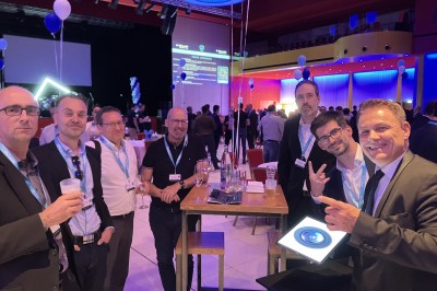 Un homme en costume tenant une tablette affichant des applications, avec un smartphone placé devant l'écran.