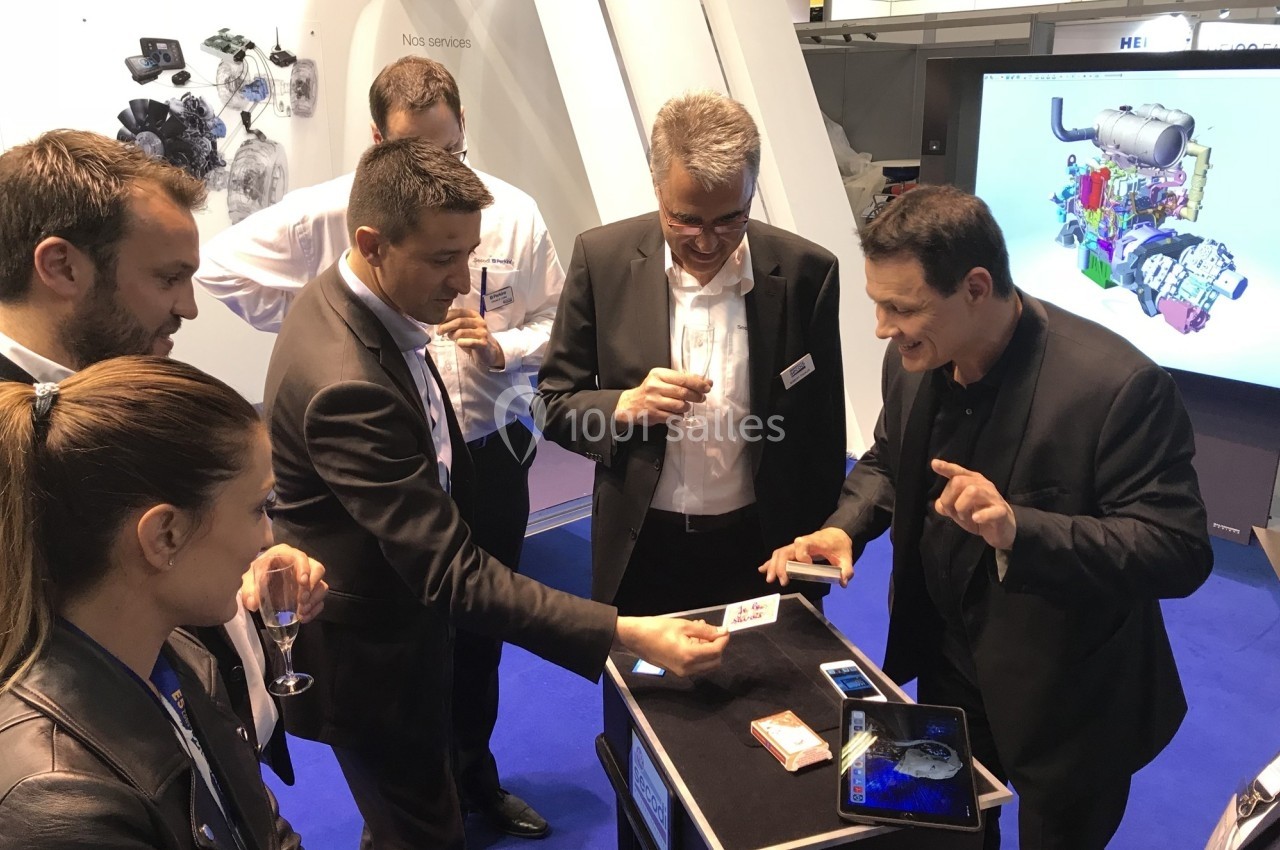 Un magicien réalise un tour de cartes devant un groupe de personnes lors d'un événement professionnel.