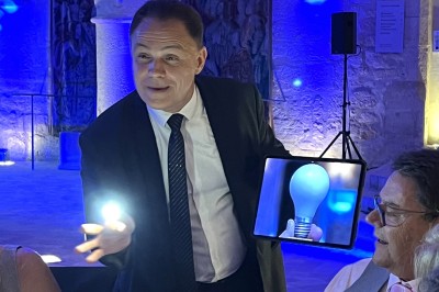 Un homme en costume tenant une tablette affichant des applications, avec un smartphone placé devant l'écran.