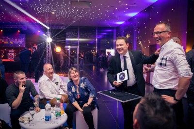 Un homme en costume tenant une tablette affichant des applications, avec un smartphone placé devant l'écran.