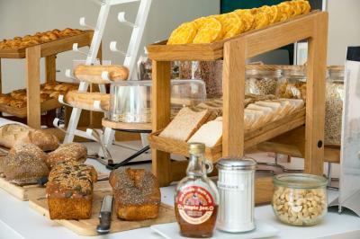 Buffet de petit-déjeuner avec œufs, saucisses, bacon et ustensiles disposés sur un comptoir blanc.