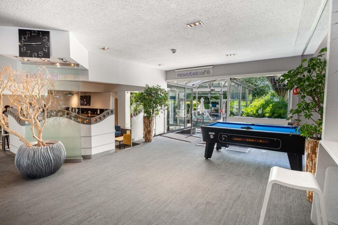 Espace lumineux avec billard, coin café et grandes baies vitrées donnant sur un jardin verdoyant.