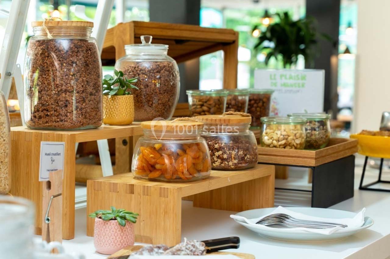 Bocaux de céréales, fruits secs et noix disposés sur des présentoirs en bois dans un espace lumineux.