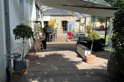 Cabane en bois avec fenêtres et porte vitrées, entourée de fleurs et d'arbustes, située près d'un chemin en gravier.