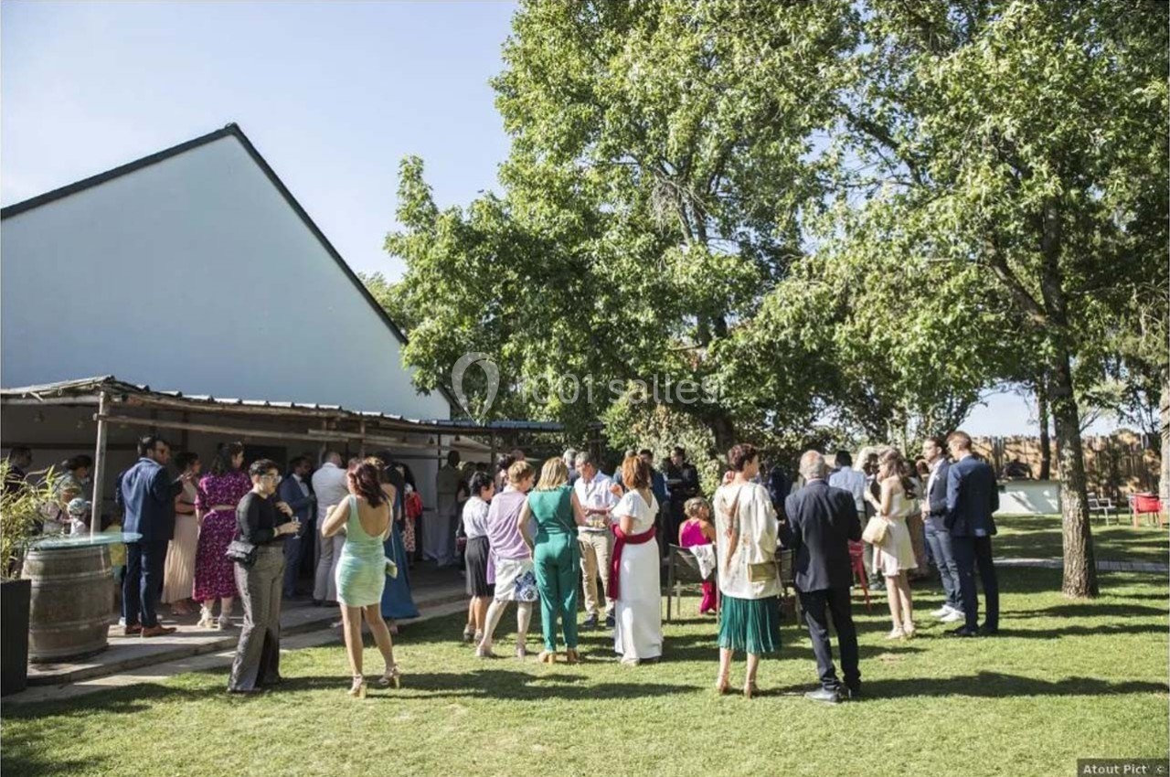 Groupe de personnes rassemblées dans un jardin lors d'un événement en plein air par une journée ensoleillée.