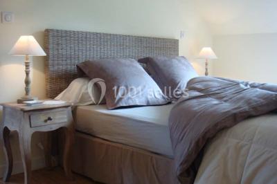 Salle à manger avec table dressée, chaises transparentes, poutre apparente, canapé bleu et tableaux au mur.